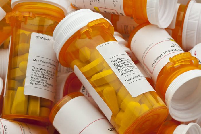 Bottles of prescription medicine in a pile. This collection of pill containers is symbolic of the many medications senior adults and chronically ill people take.