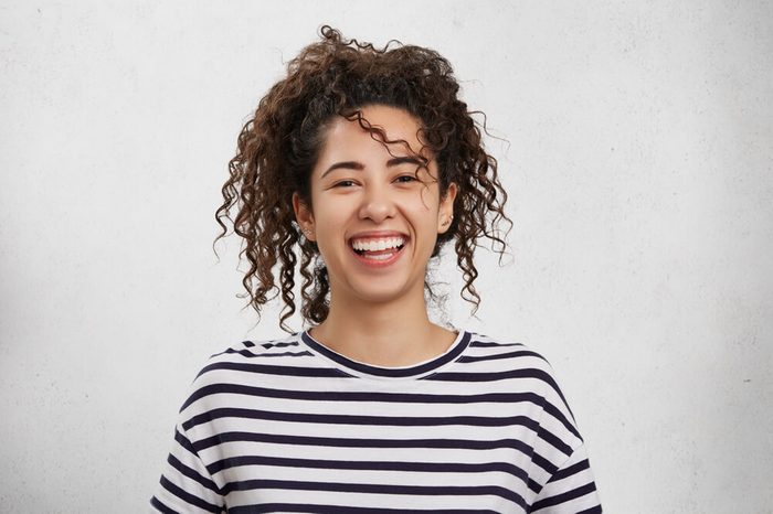 Positive emotions concept. Emotional happy young woman with crisp hair, appealing appearance and broad charming smile, rejoices her success or being glad to organize unforgettable party with friends