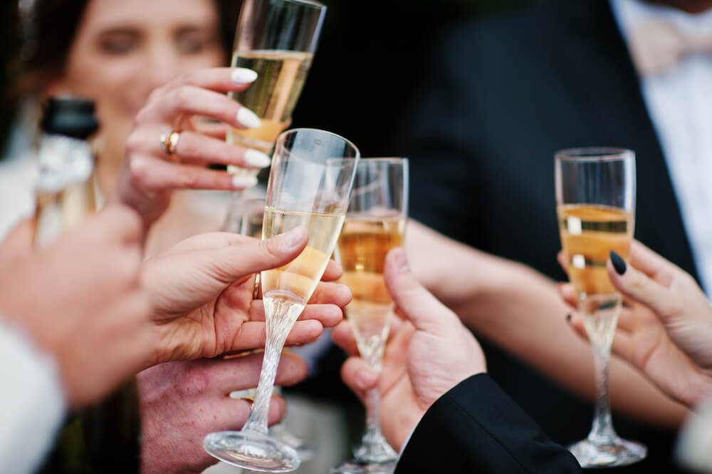 Wedding couple, bridesmaids and groomsmen drinking champagne outside.