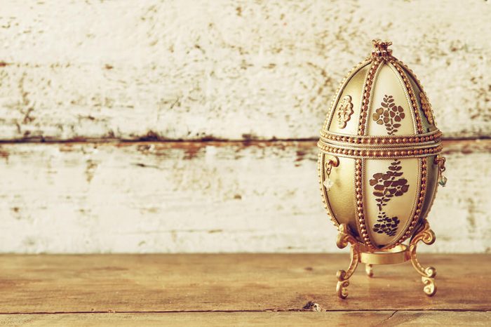 image of gold faberge egg on wooden table. vintage filtered