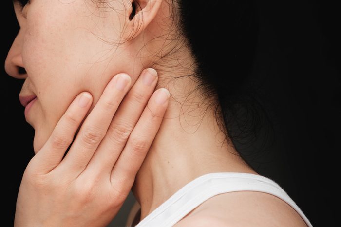 woman with cheek pain or chin pain.Acute pain in a woman Salivary gland . Female holding hand to spot of nape-aches. Concept photo with read spot indicating location of the pain.