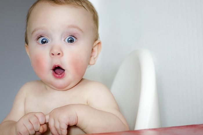 surprised kid sitting at table. child's eyes widened and mouth opened in amazement. copy space for your text