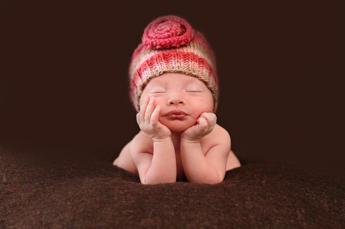Beautiful newborn baby resting her hands on her face