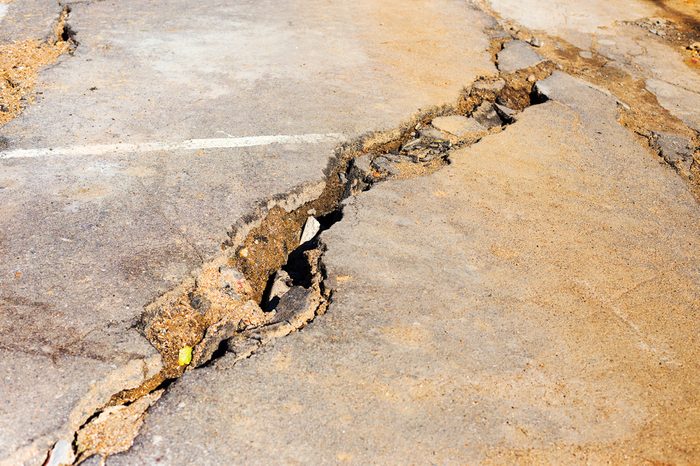 Huge cracks on pavement due to natural disasters, landslide, earthquake. Broken coating of asphalt leading to pothole, dangerous for vehicles pedestrians. Of poor road emergency situations