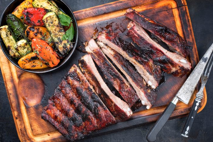 Barbecue spare ribs St Louis cut with hot honey chili marinade sliced as top view on an old rustic board