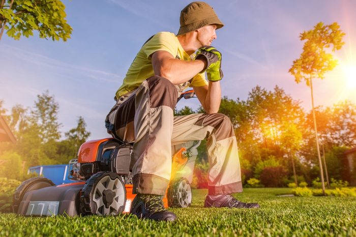 Garden is My Hobby and My Passion. Passionate Caucasian Men Watching His Beautiful Garden While Seating on His Grass Mower After Hard Working Day. Garden Lover.