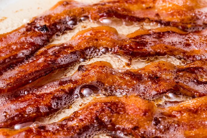 bacon cooked cooking in white pan skillet on flat top stove