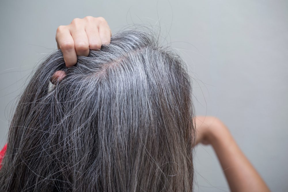 woman is checking white hair white looking at the mirror