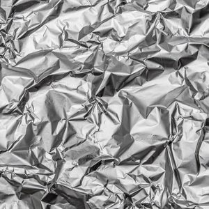 Crumpled aluminum foil creates a textured, reflective surface in varied light.