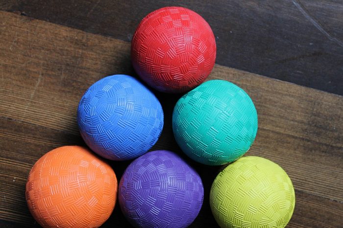 Colorful textured balls arranged in pyramid shape on wooden floor.