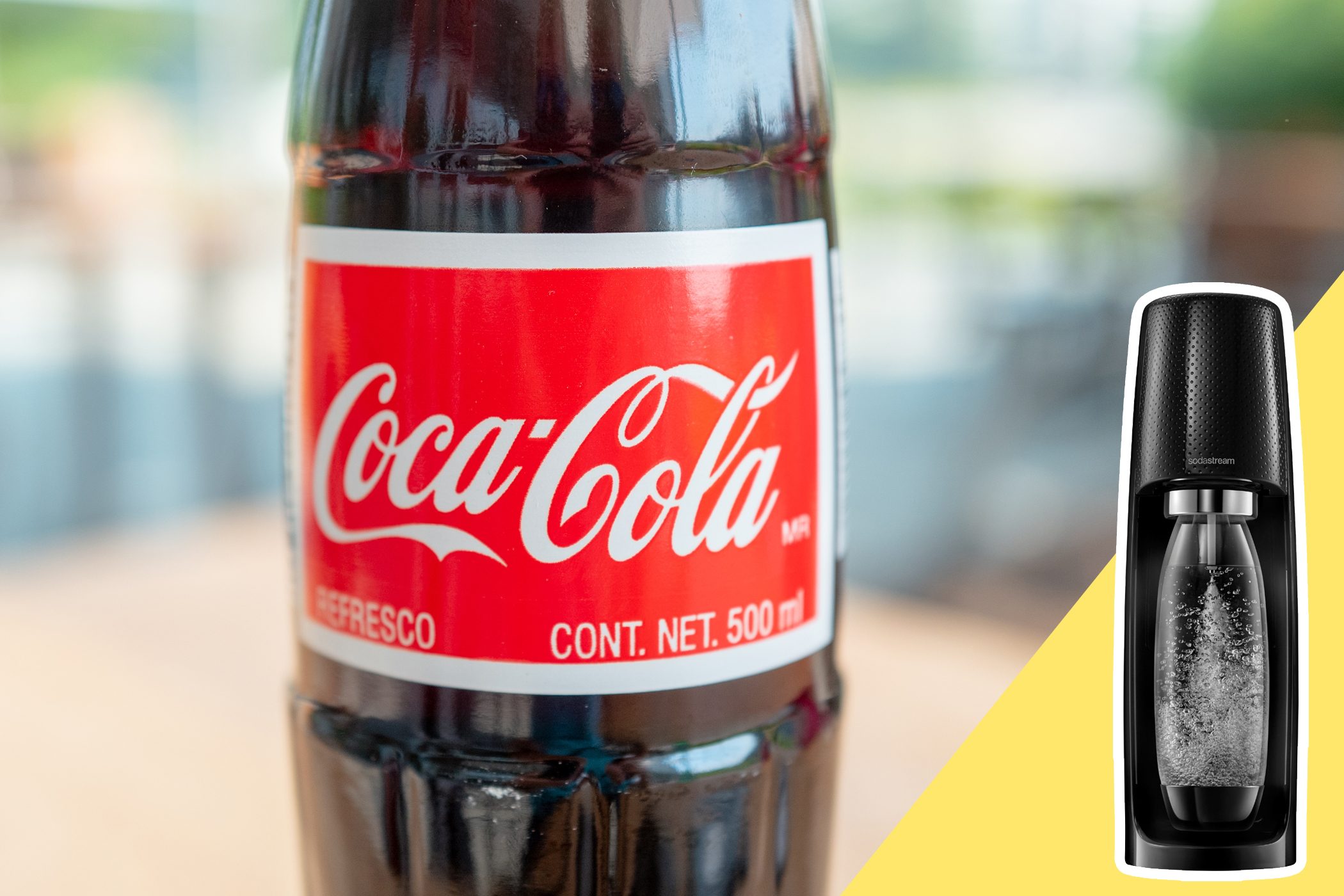 Coca-Cola bottle stands on a blurred background; beside it, a SodaStream machine with a fizzing bottle, set against a yellow diagonal backdrop.