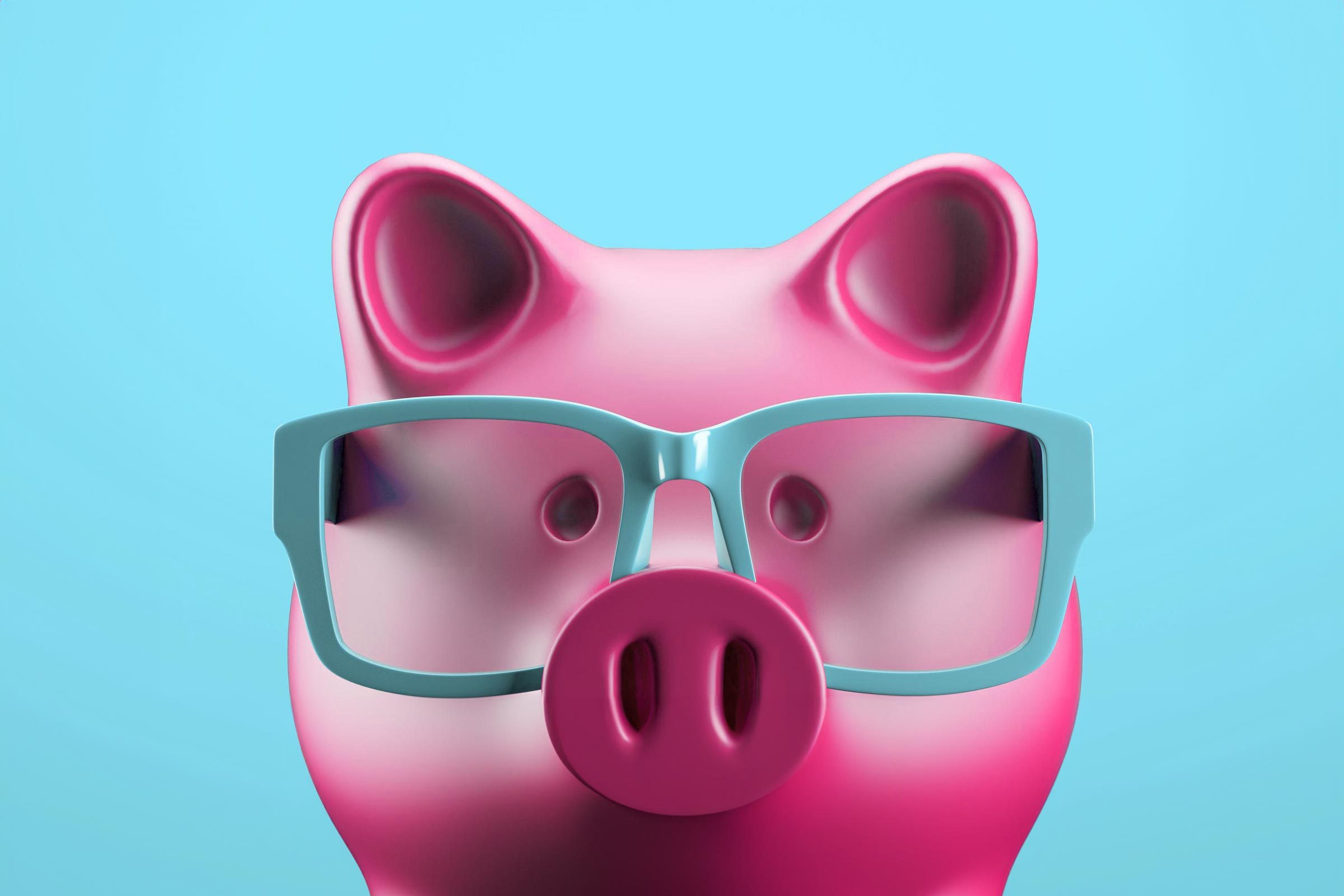 A pink piggy bank wears blue glasses against a solid light blue background.