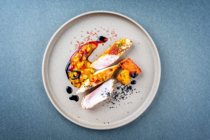 Modern barbecue crocodile tail eye fillet with roasted sweet potatoes pineapples and mango chili chutney as top view on a plate