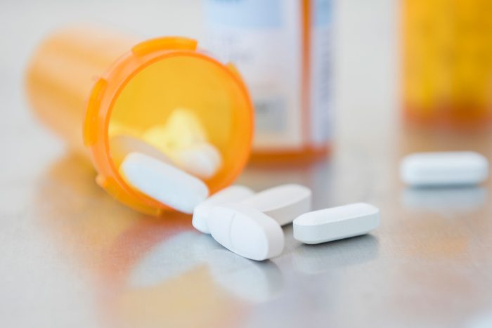 close up pills spilling out of an orange prescription bottle