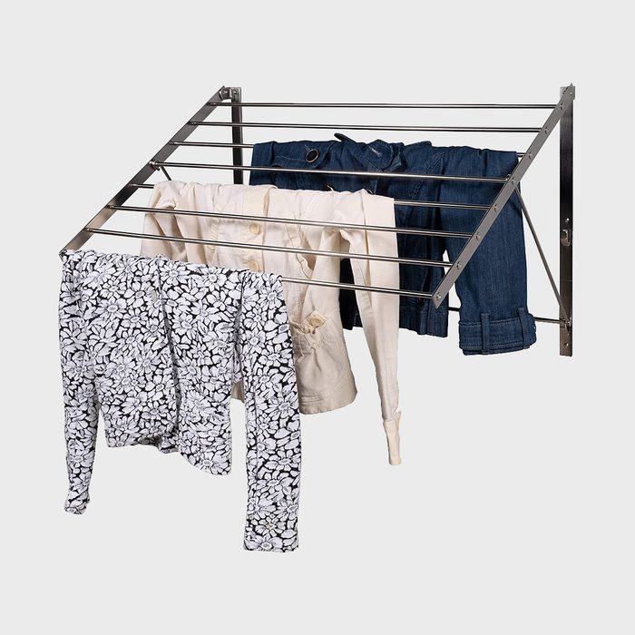 A wall-mounted drying rack holds patterned and plain clothing, extended horizontally, set against a plain grey background.