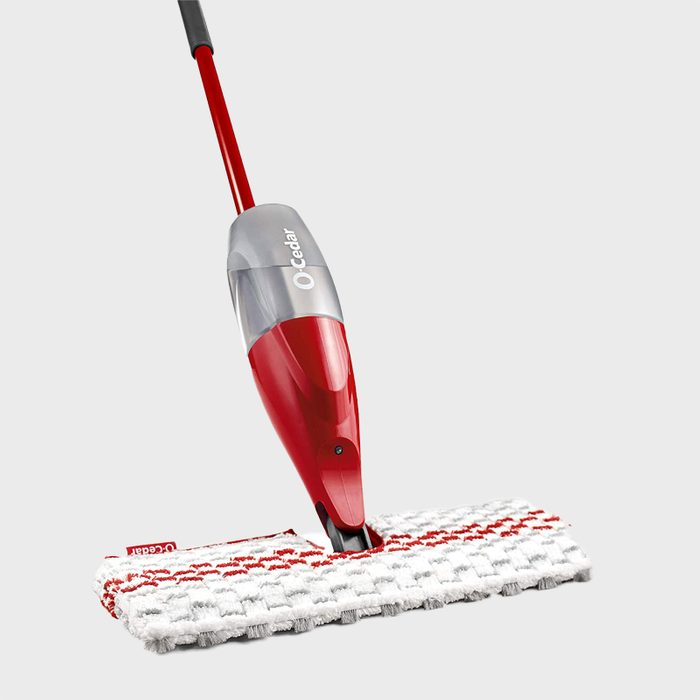 Red mop sprays liquid, attached to a white and red microfiber pad, set against a plain gray background. Contains text: 