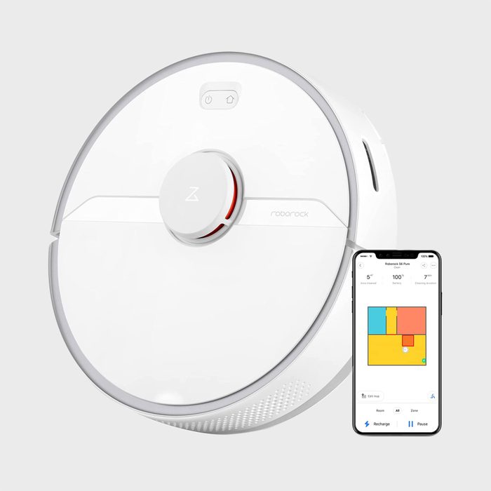 Robotic vacuum cleaner next to smartphone displaying cleaning map; both on a light gray background.