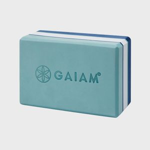 A teal yoga block rests against a light background, displaying the word 