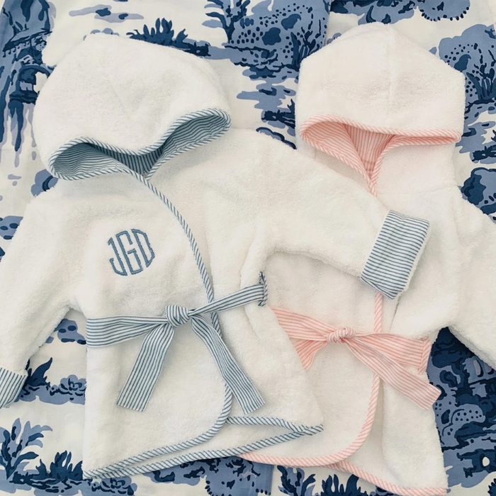 Two hooded robes lay side by side, tied with belts; one has blue trim and 