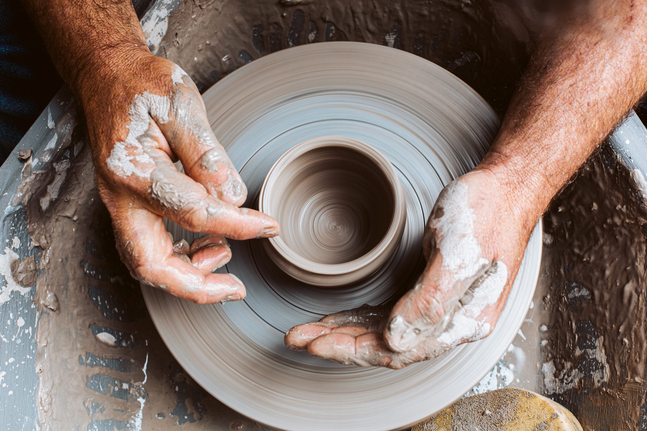 Potter's hands working clay on a potter's wheel