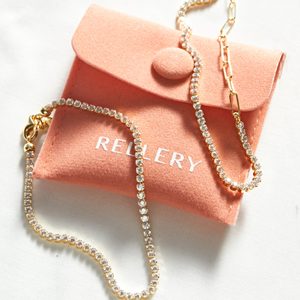 Jewelry rests on a pink pouch labeled 