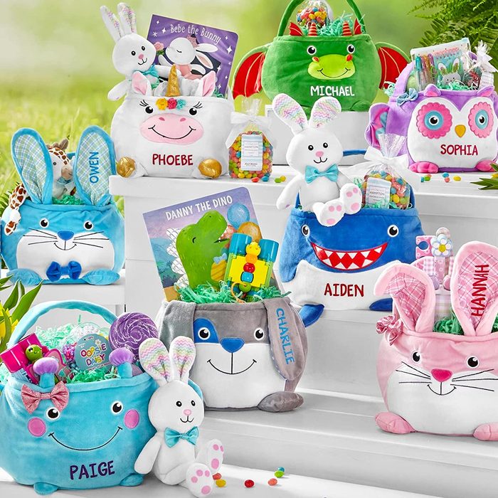 Colorful plush baskets hold toys and candy, labeled with names. Surrounding a grassy outdoor setting, each basket has a unique animal design.