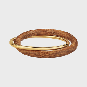 Two intertwined rings with one gold and one wood-textured, resting against a plain white background.