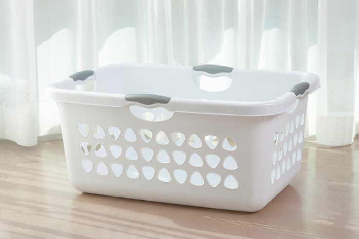 Empty white laundry basket on floor.