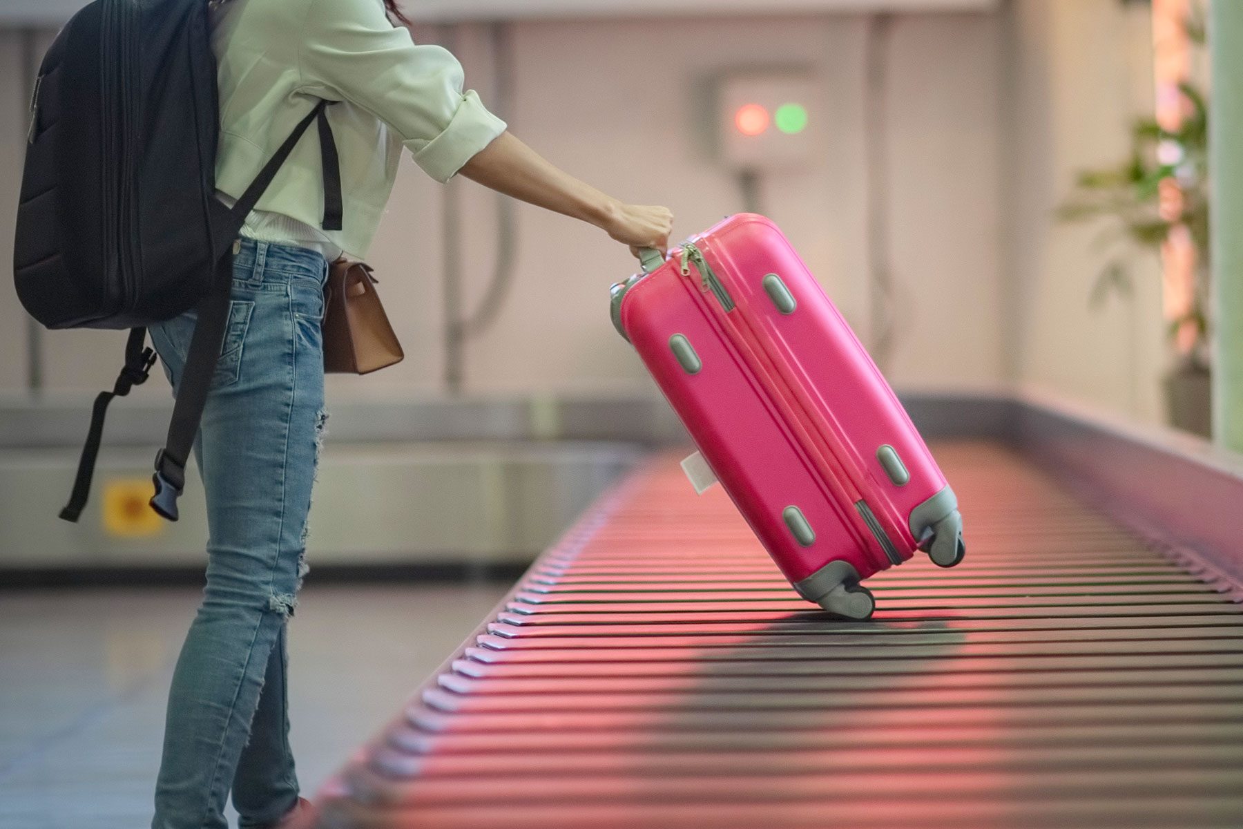 Female Traveler claims her luggage in the reclaim area of the airport