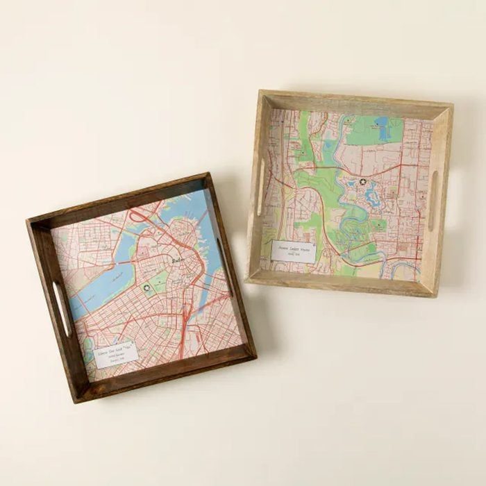 Two wooden trays display colorful city maps inside, lying on a light surface.