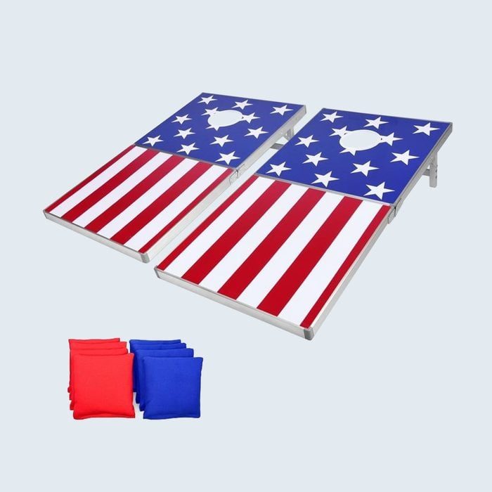 Bean bag boards, decorated with American flag designs, set for cornhole game; red and blue bean bags positioned nearby on a plain background.