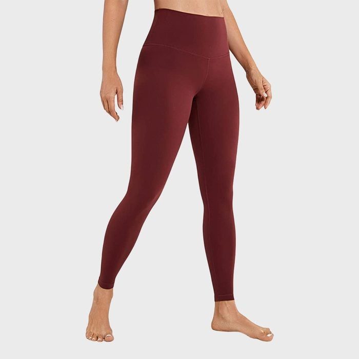 Person showcases maroon leggings, standing barefoot against a plain gray background.
