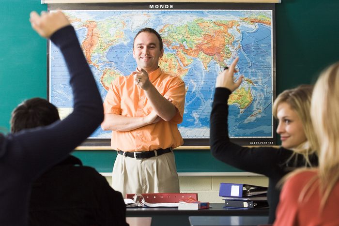 teacher in classroom standing in front of pulled down map