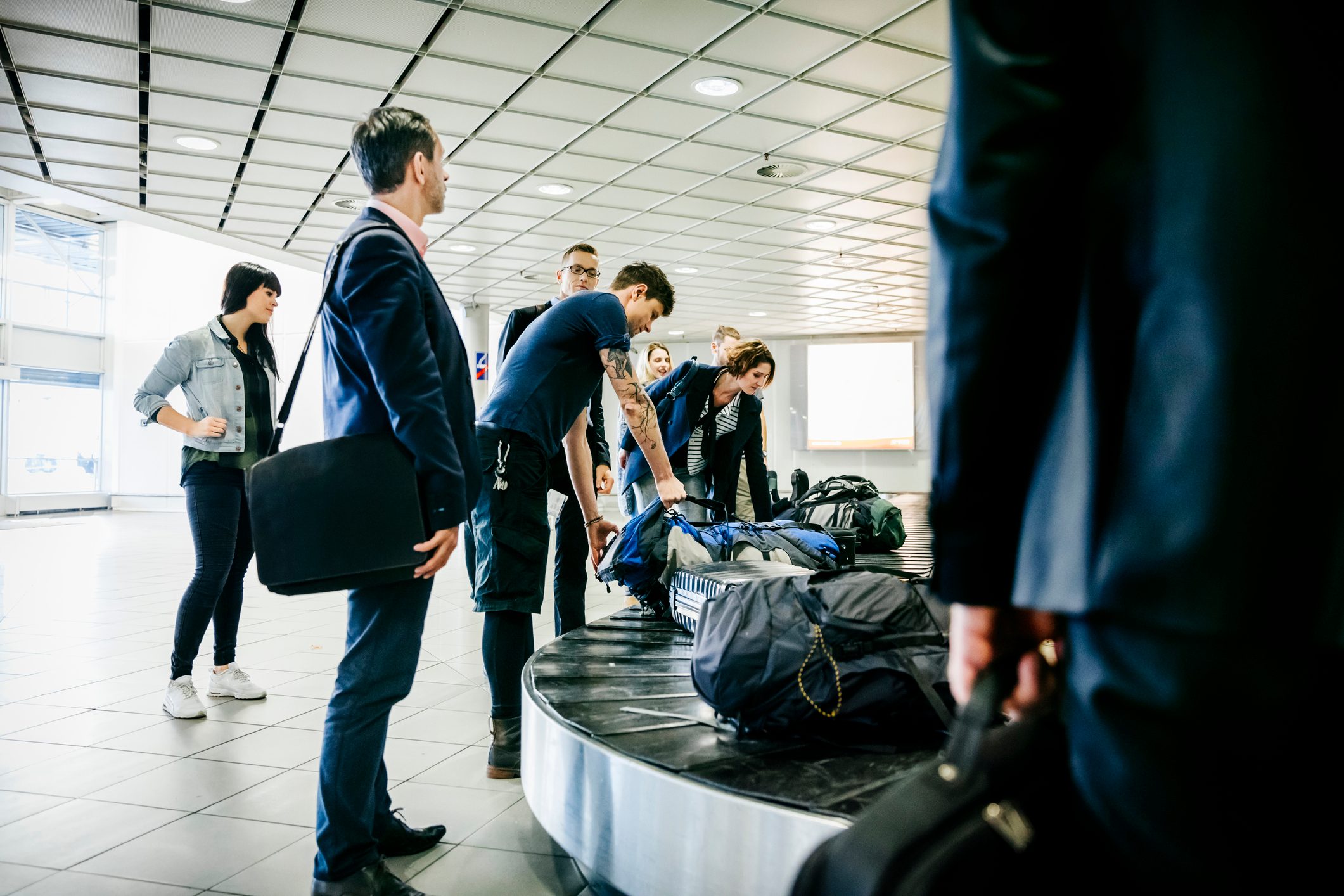 Group of travellers waiting for their luggage at baggage claim