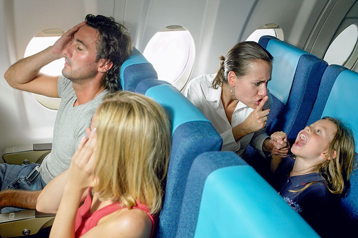 Girl (5-7) yelling behind young couple in airplane